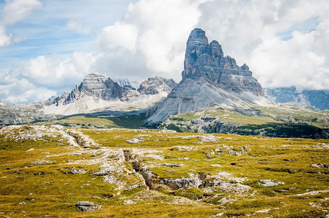 rock formation on wide field grass under cloudy blue sky during daytime