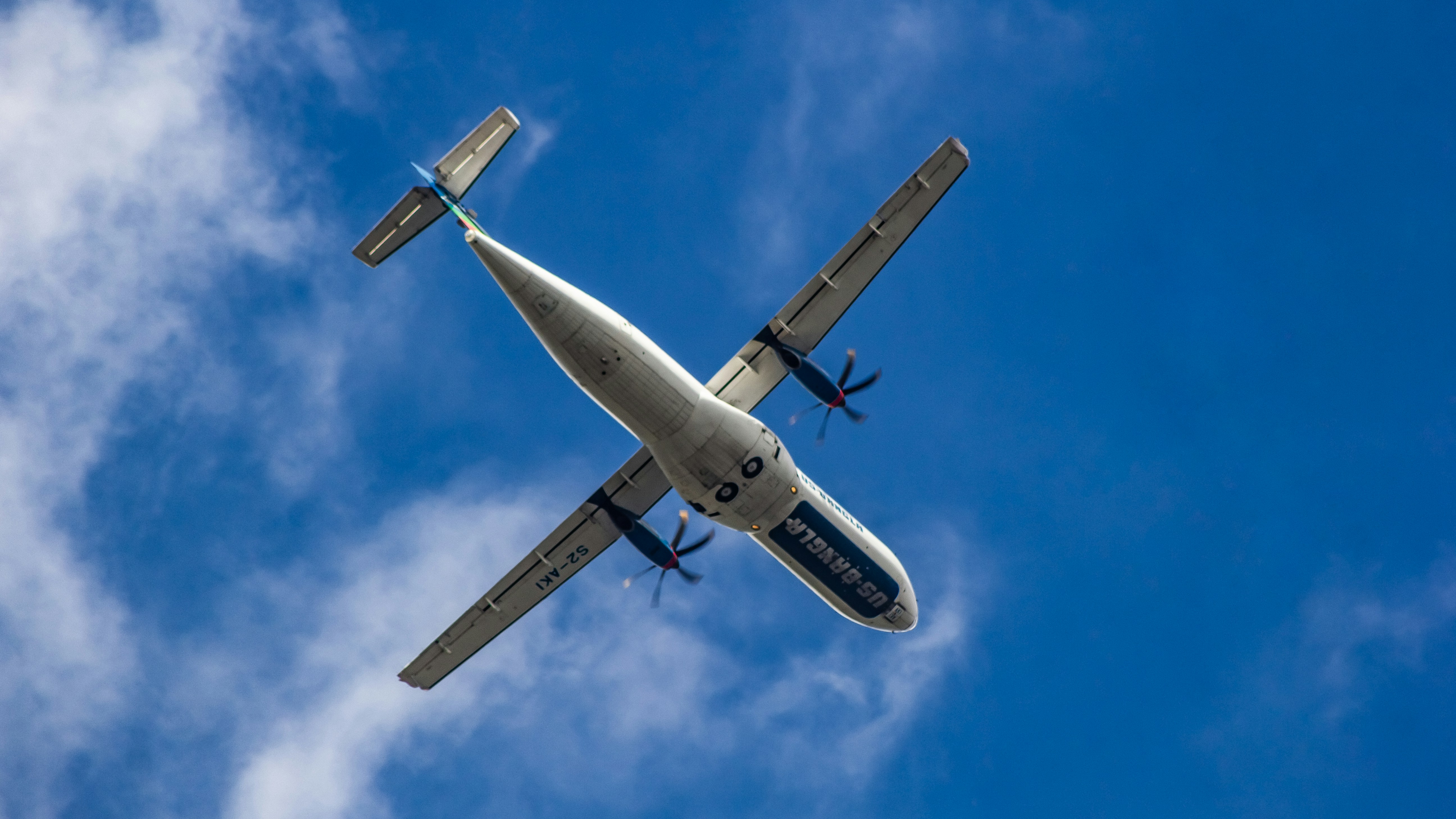 A small plane flying through a blue cloudy sky